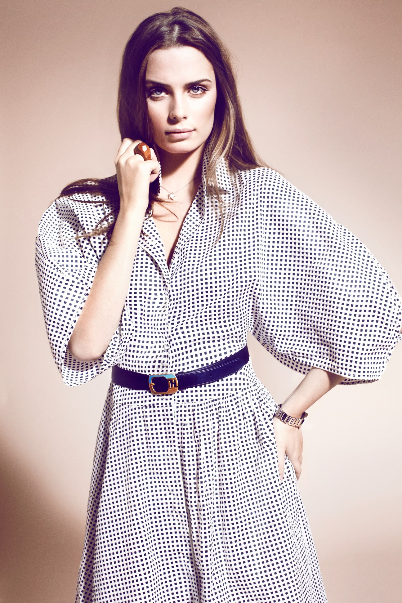 Woman in polka dot Fendi dress with Chanel necklace and Rado watch, posing against neutral background.