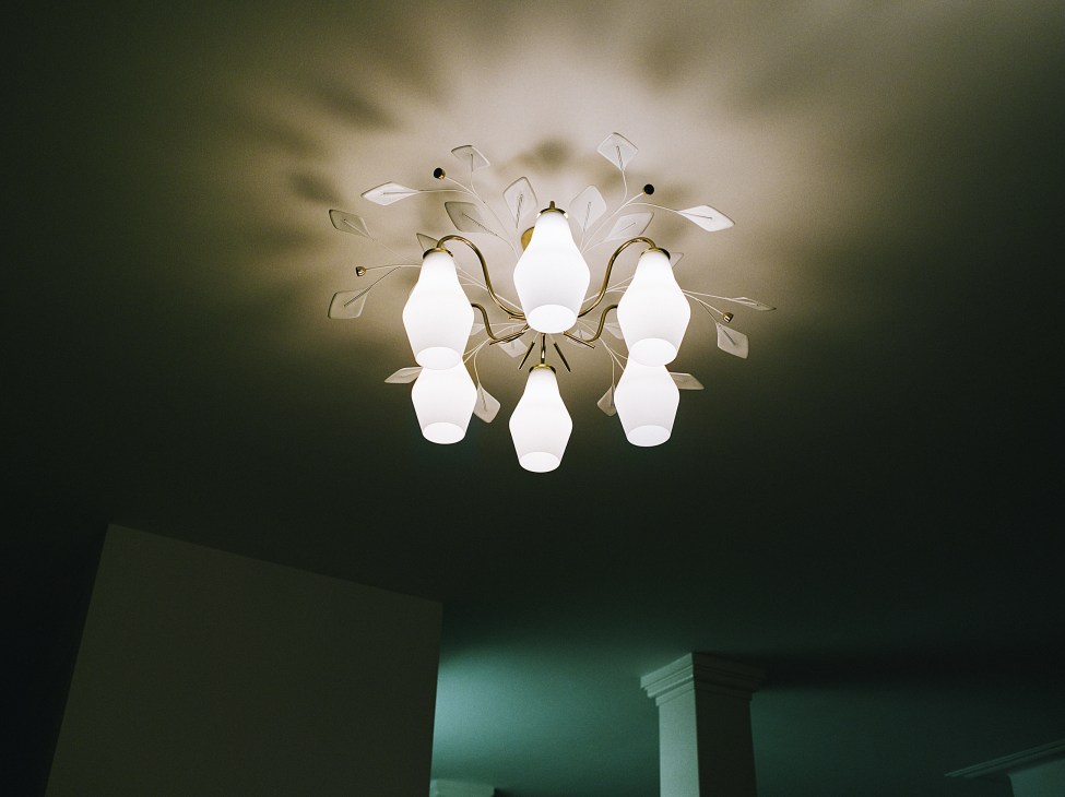 Chandelier by Paavo Tynell featuring white glass bulbs suspended from brass branches against a dark ceiling.