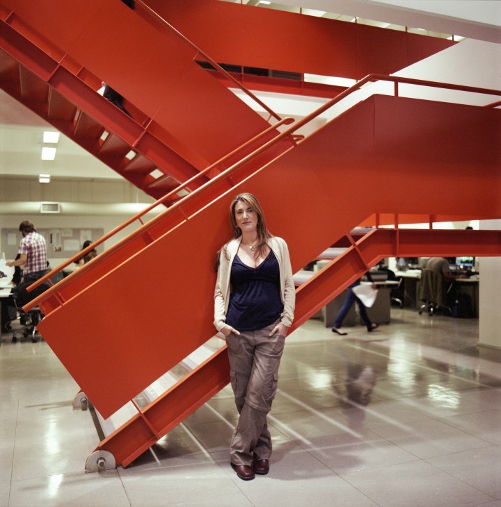 Patricia Pata Campos Mello, columnist at Folha de S.Paulo, stands in the modernised newsroom with distinctive red staircase behind her.