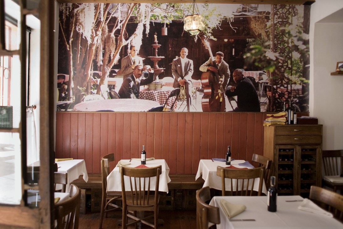 Anderson's steak house interior with dining tables, wooden chairs, and vintage mural of men in suits.