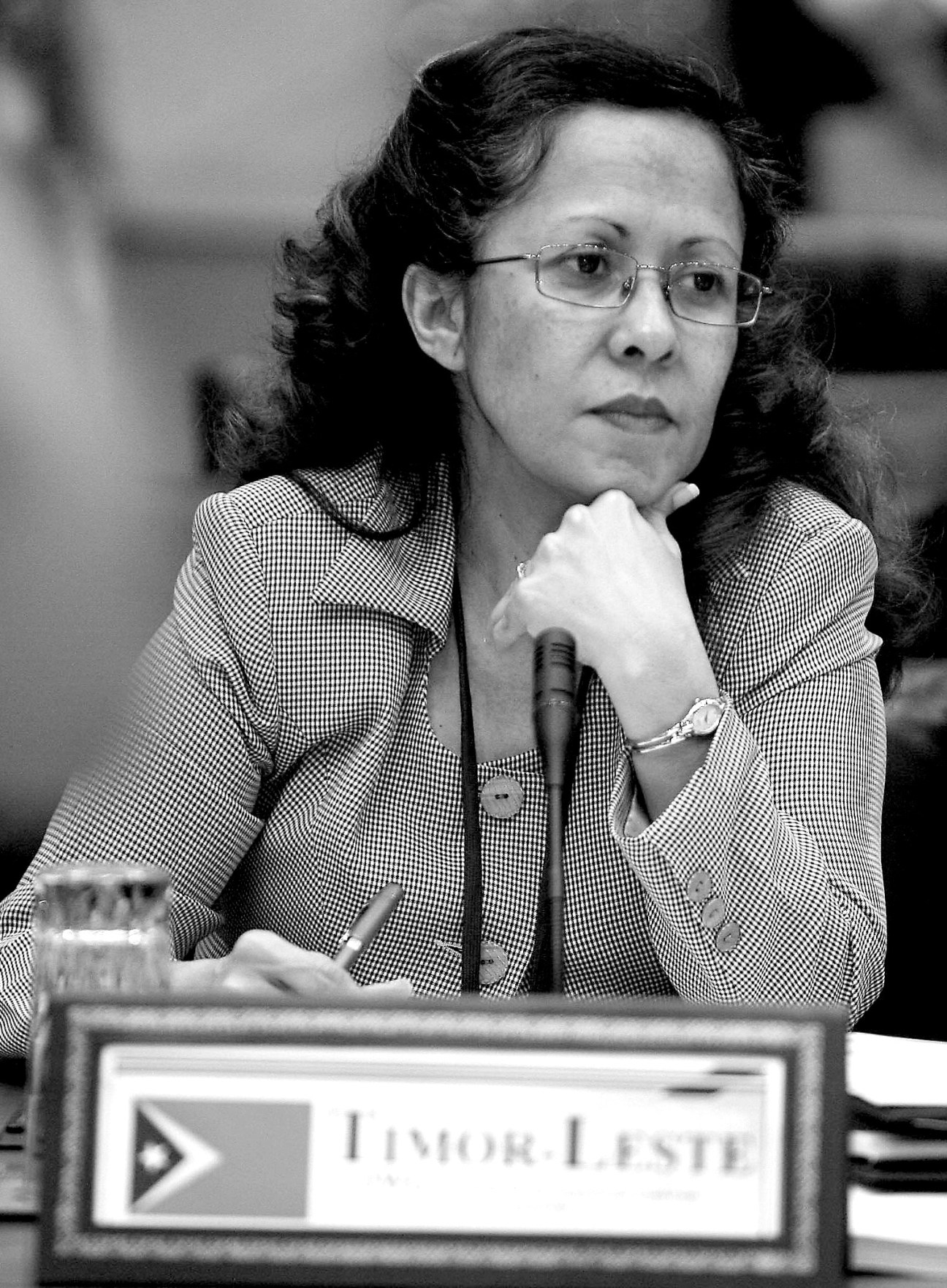 Black and white photograph of Emilia Pires, Timor-Leste's finance minister, at a formal event with a microphone.