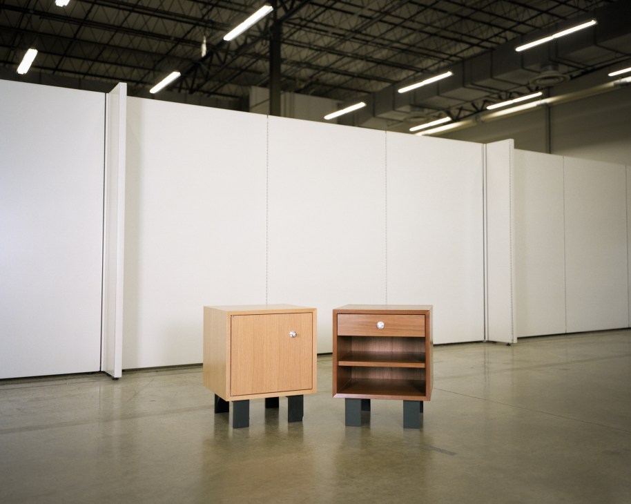 Two wooden cabinets from Nelson's Basic Cabinet Series displayed in a minimalist gallery space with industrial ceiling.