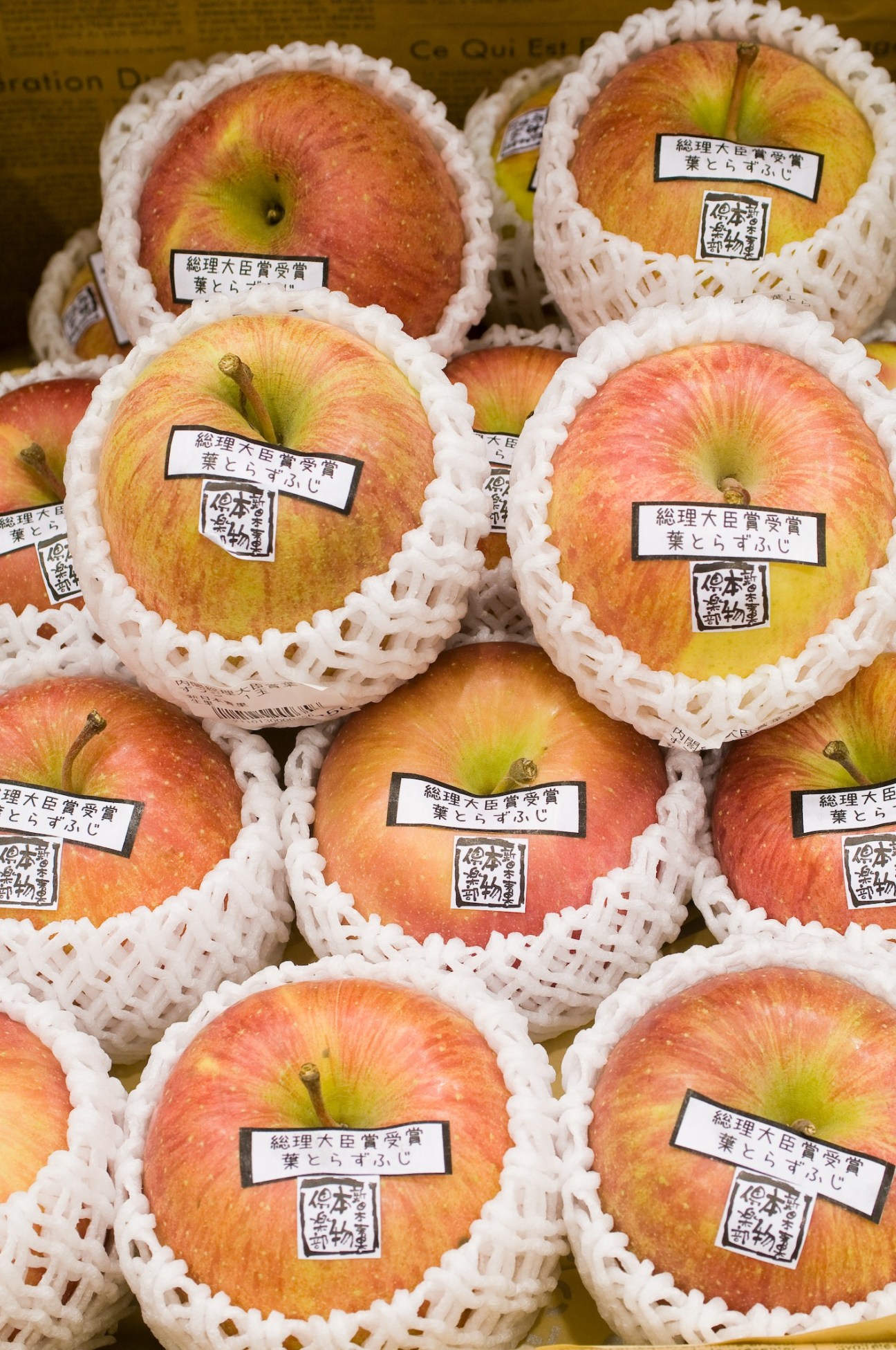 Hatorazu Fuji apples individually wrapped in white netting with Japanese labels.
