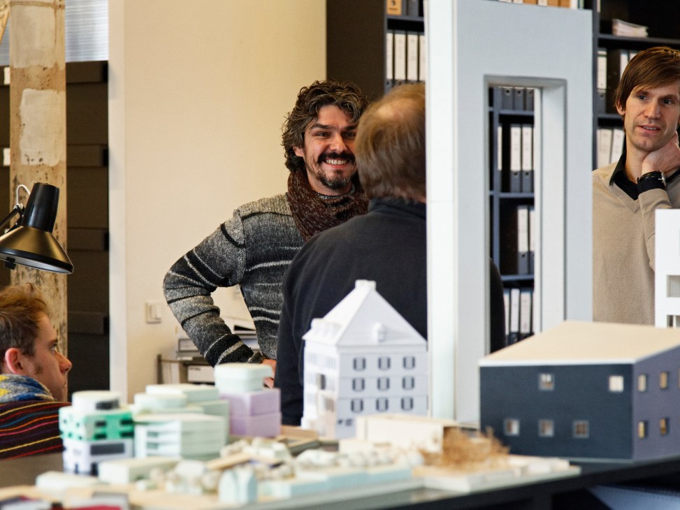 Architects converse beside architectural models in the first-floor design studio.