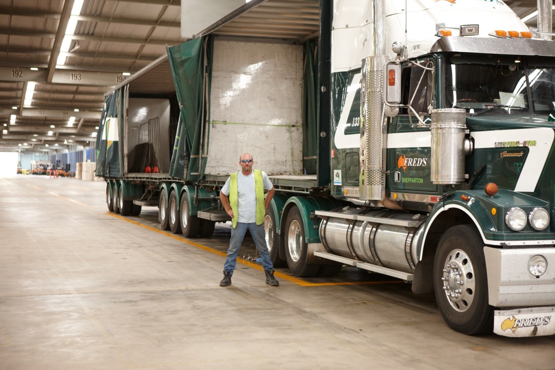 A trucking sub-contractor stands between loaded semi-trailers at Yennora Wool Selling Centre warehouse.