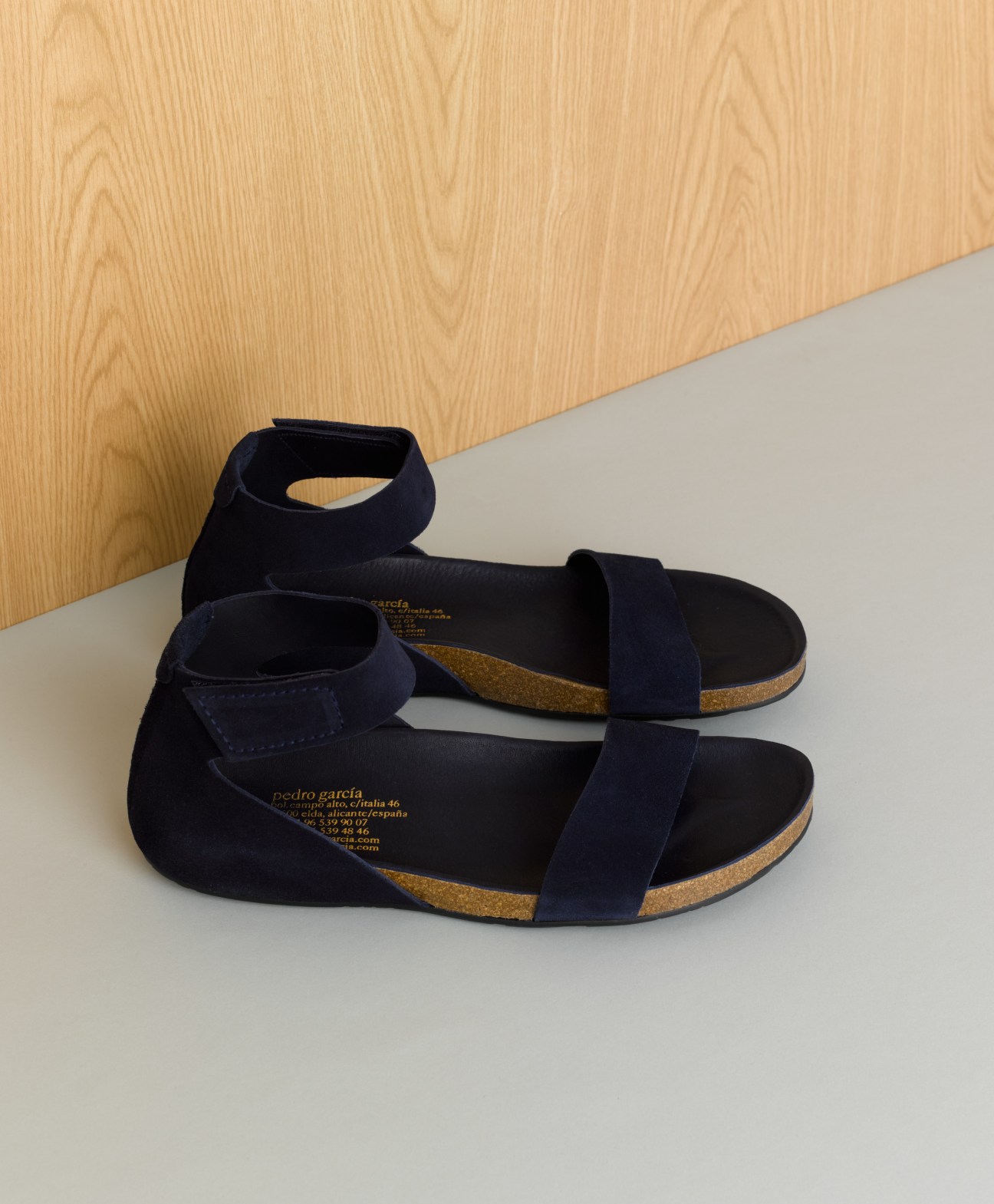 Pedro García men's sandals with navy suede straps and cork soles on a minimalist background.