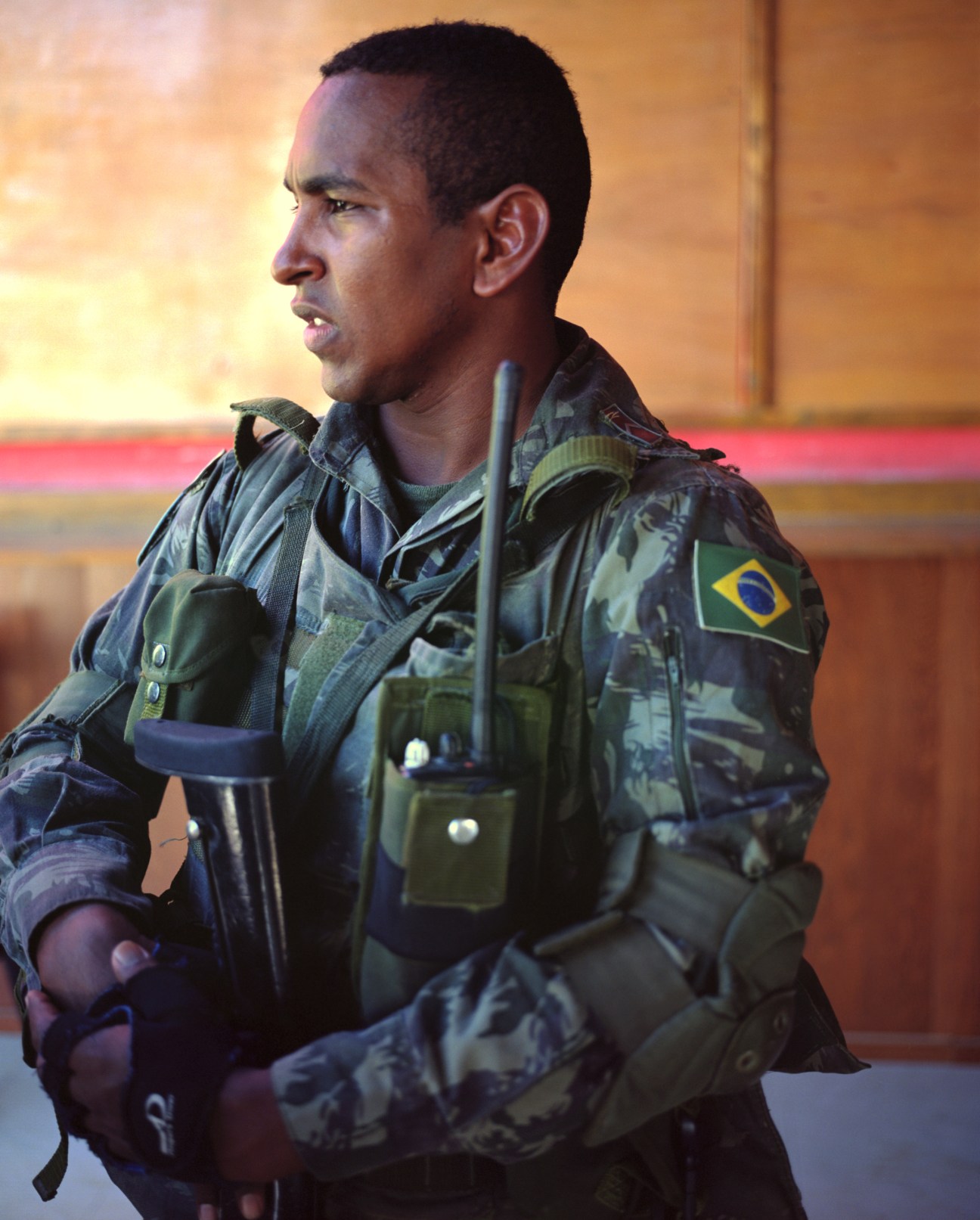 Brazilian soldier Private Mauricio Rodrigues Santos in military fatigues with Brazilian flag patch at Cité Soleil base.