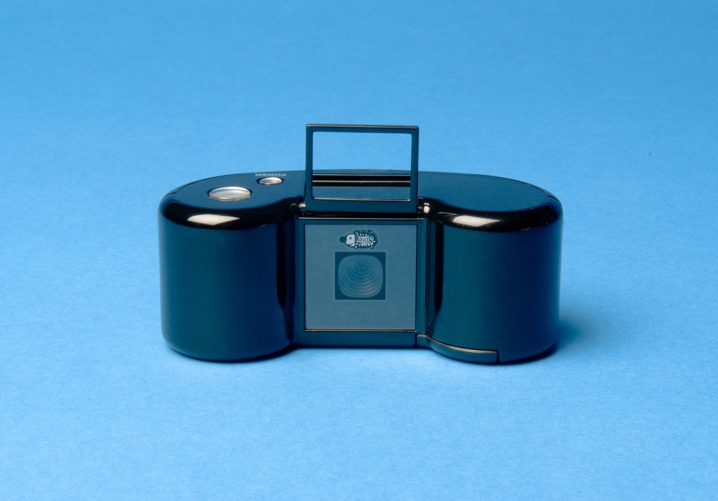 Digital Harinezumi 2 retro-style camera with dark blue cylindrical body and viewfinder against blue background.