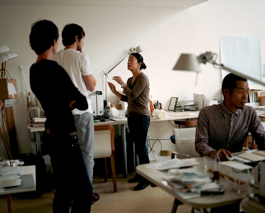 Tomoko Azumi briefs staff in her minimalist design studio filled with models and design materials.