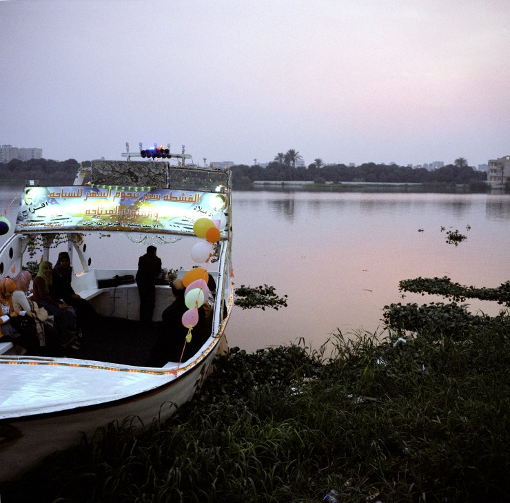 Entertainment boat with passengers and Arabic signage on a waterway near Suez Canal.