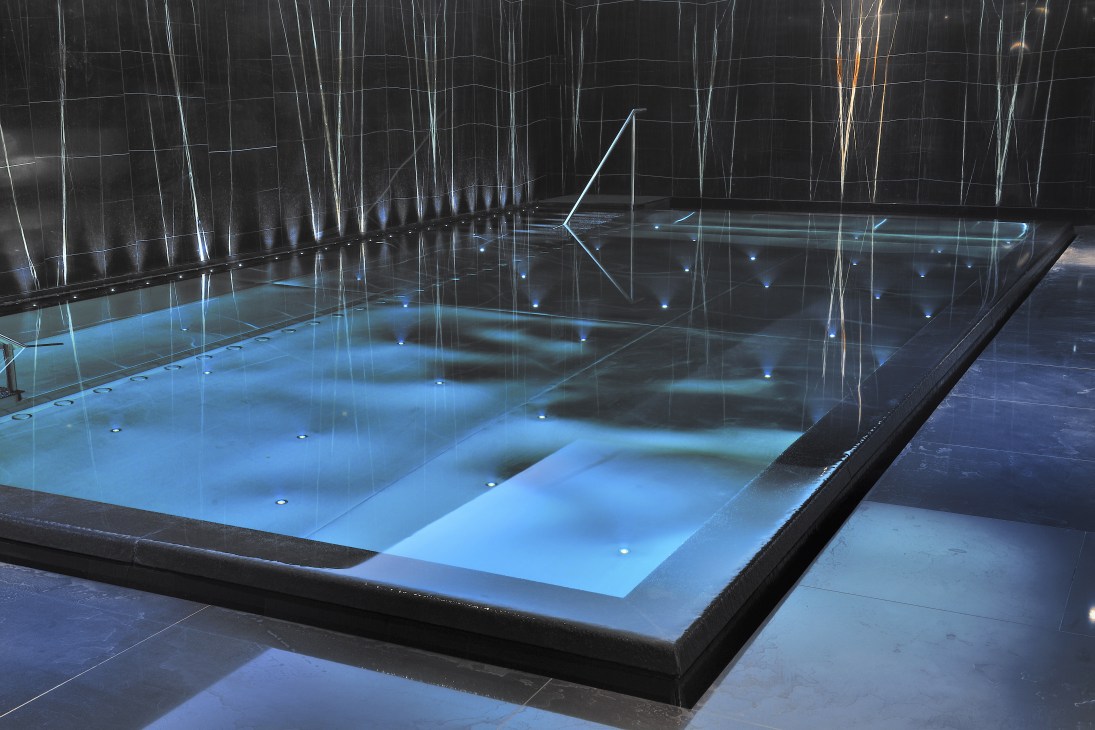 Modern spa swimming pool with blue lighting and reflections on ceiling at Espa Life, Corinthia hotel London.