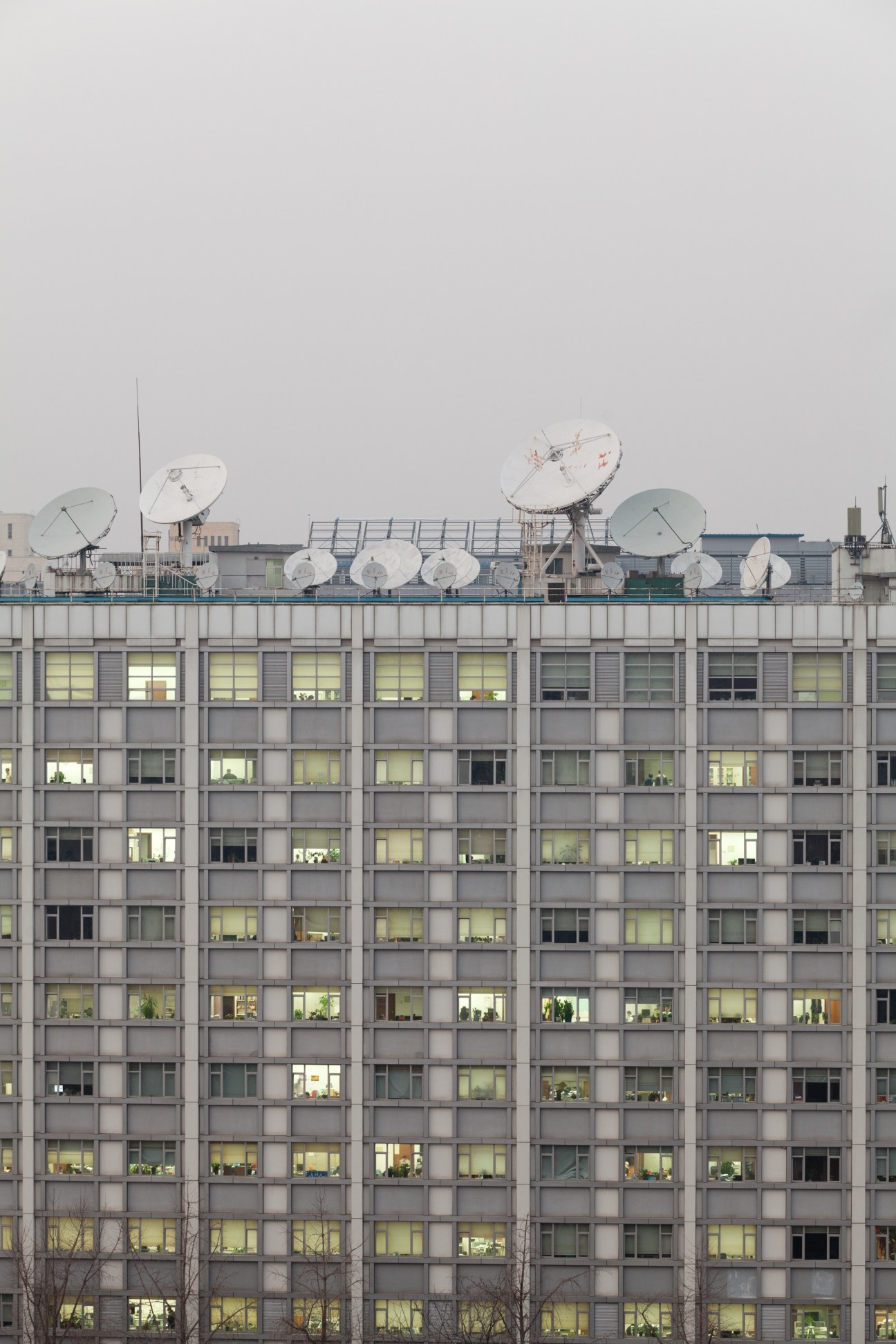 Satellite dishes on the rooftop of a gray Xinhua office building in Beijing.