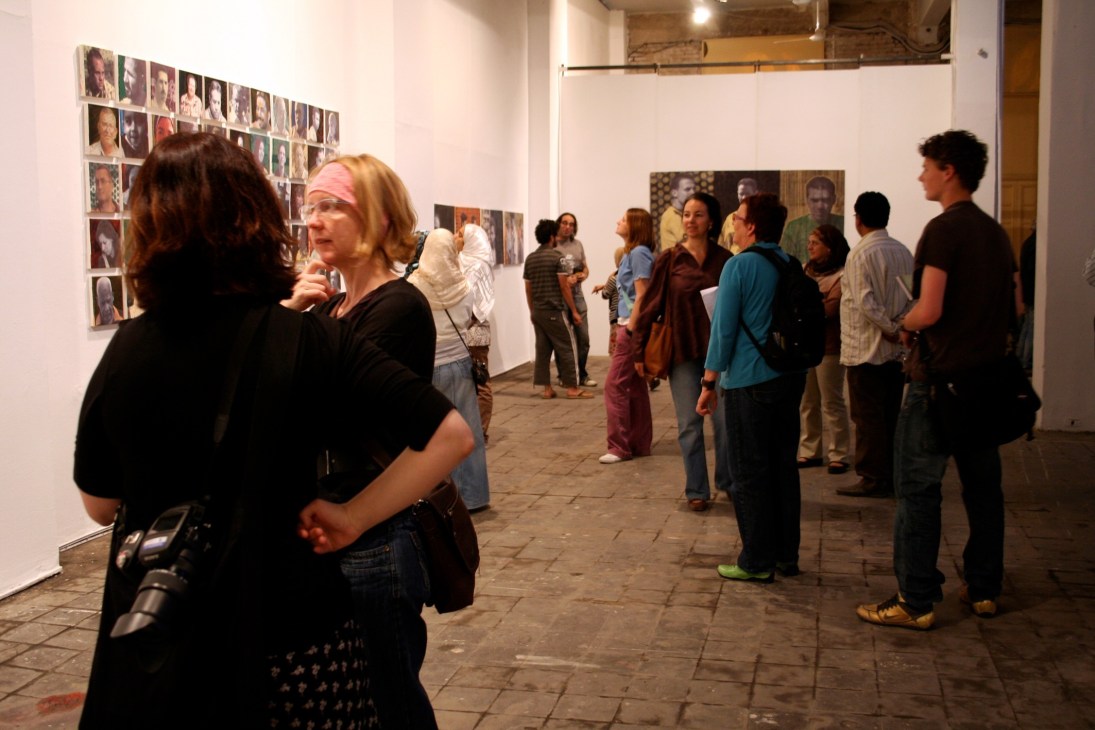 Visitors at Townhouse gallery in Cairo viewing portrait photographs displayed on white walls.