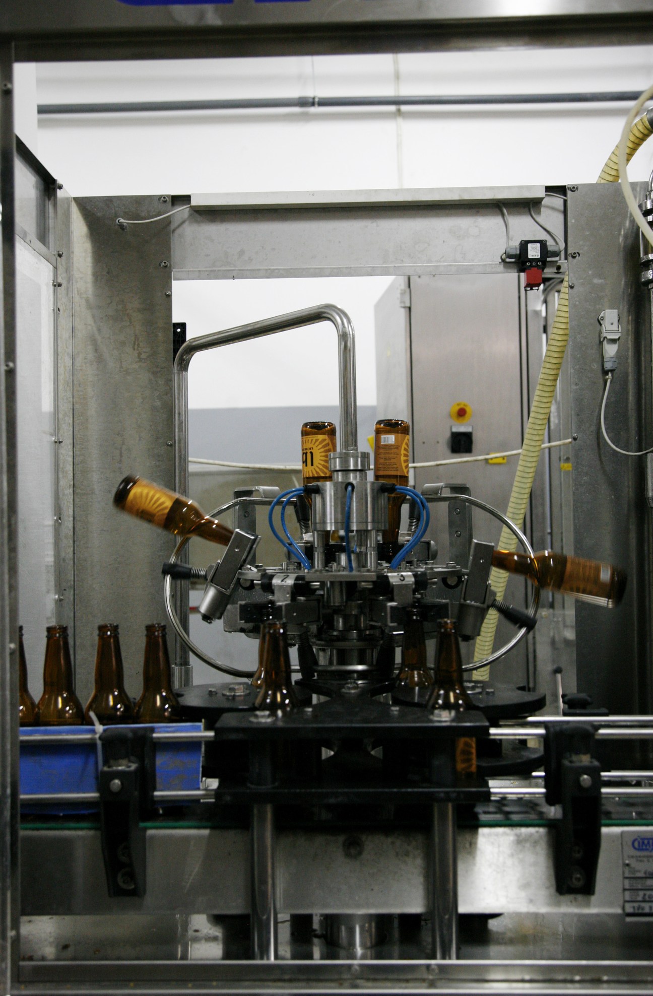 Automated beer bottling machine filling brown glass bottles with LB beer in a brewery facility.
