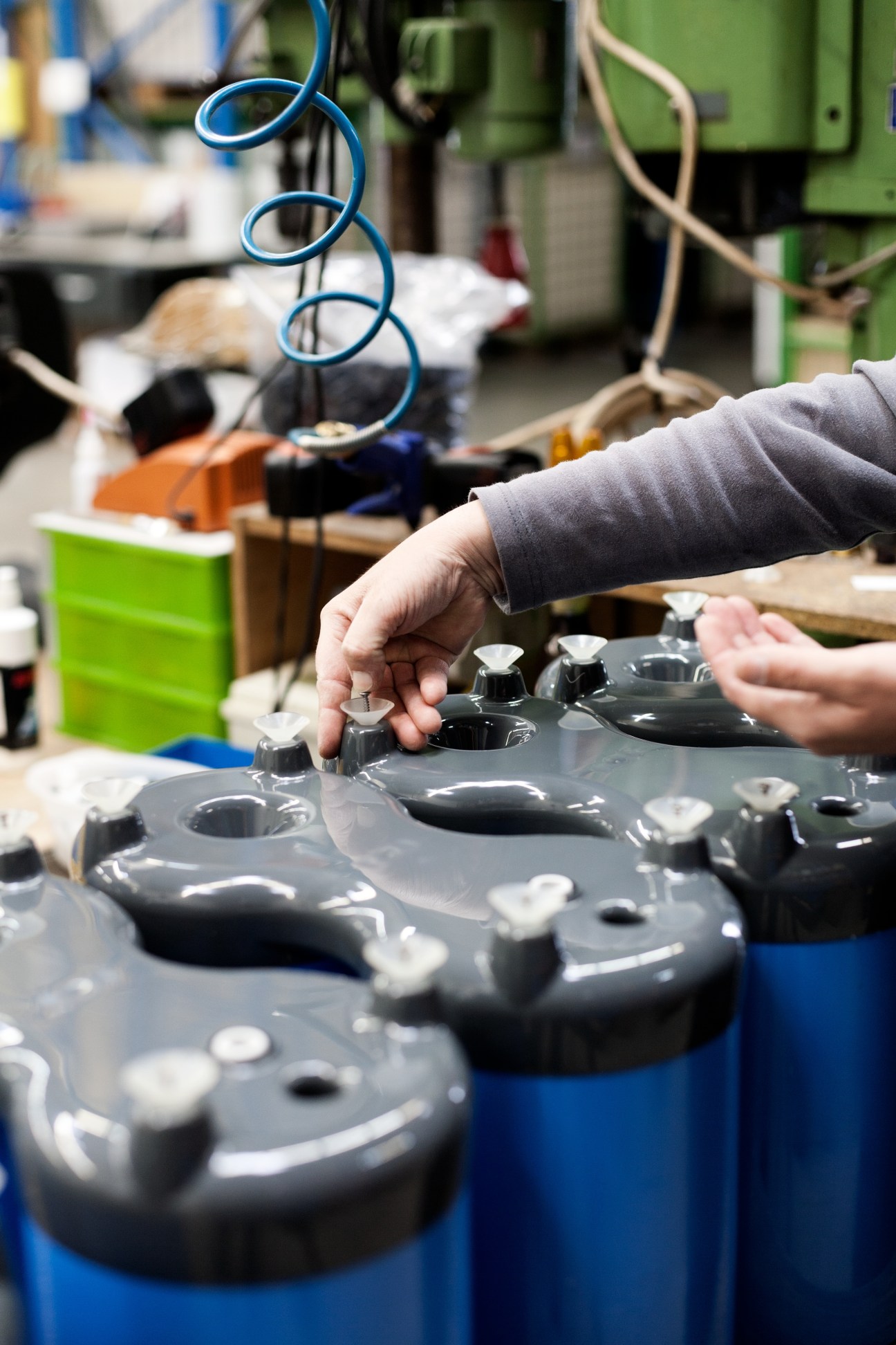 A worker inspects blue and grey Spülboy glass washer components during assembly at the factory in Wuppertal, Germany.