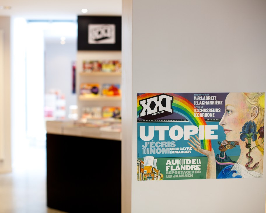 XXI magazine cover displayed on a white wall beside a blurred bookshop interior