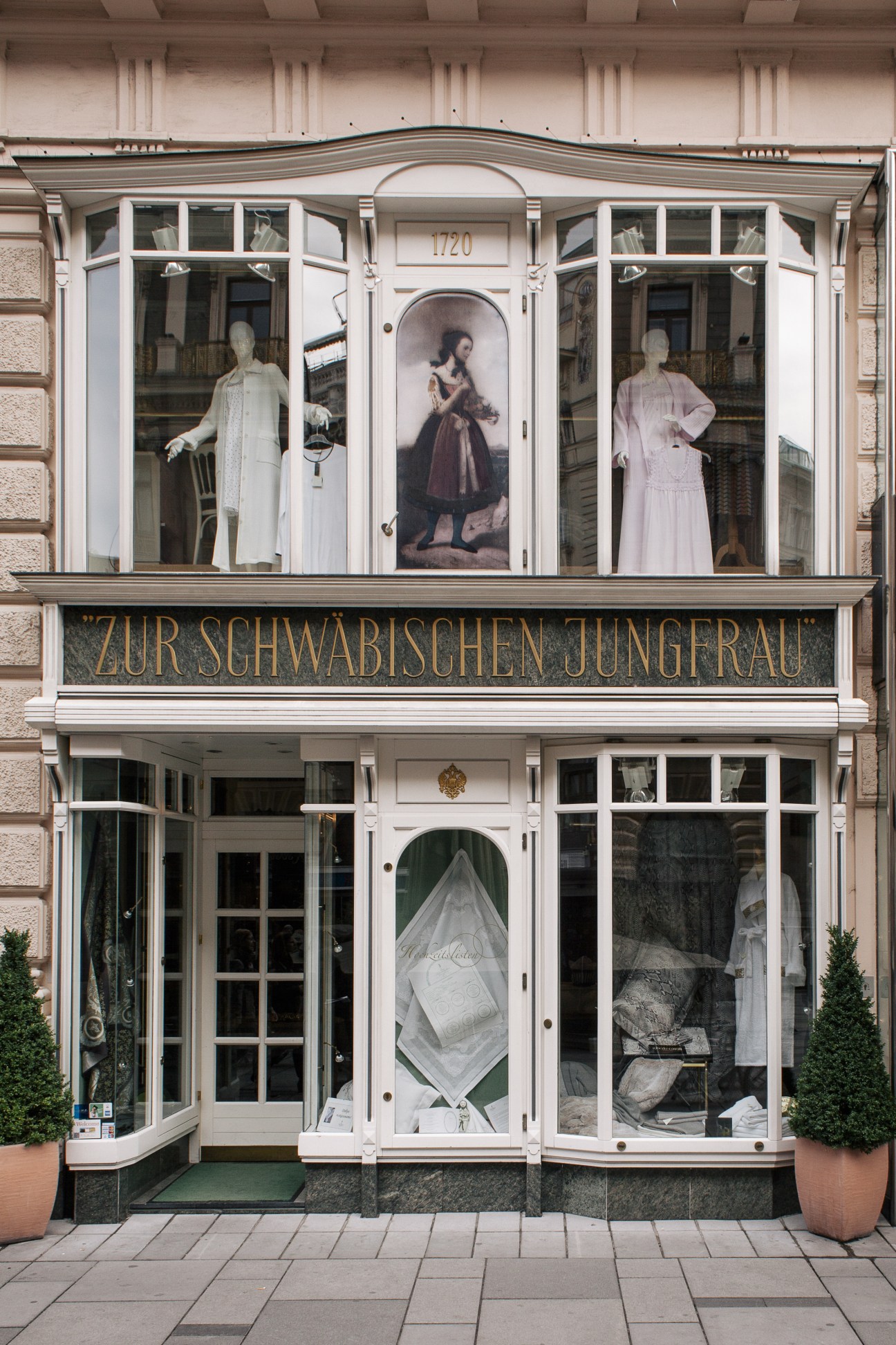 Facade of Zur Schwabischen Jungfrau homeware shop with window displays showing clothing on mannequins.