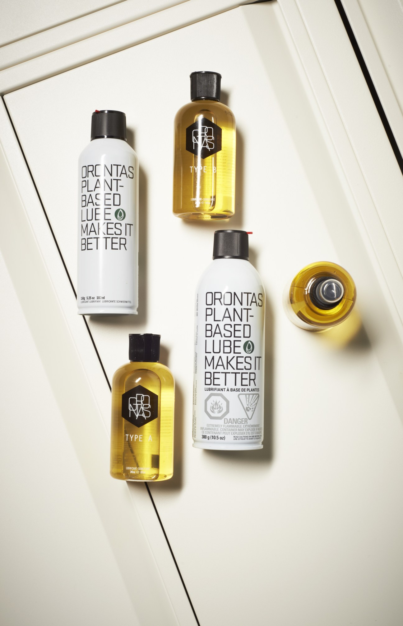 Orontas plant-based bike lubricant bottles in yellow and white packaging arranged on a white surface.