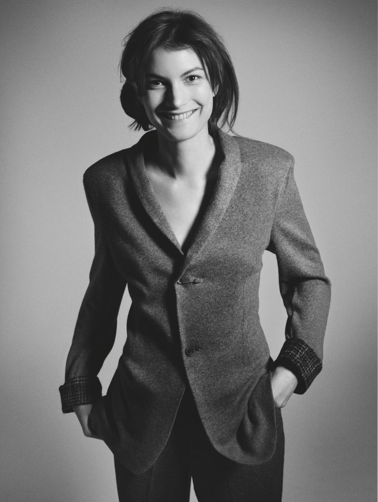 Woman wearing a grey wool blazer with checked cuffs and dark trousers by 1205.