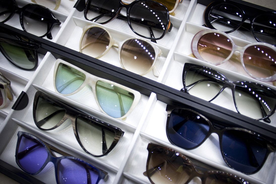 Ralph Vaessen handmade eyewear collection displayed in white compartments showing various frame styles and lens tints.