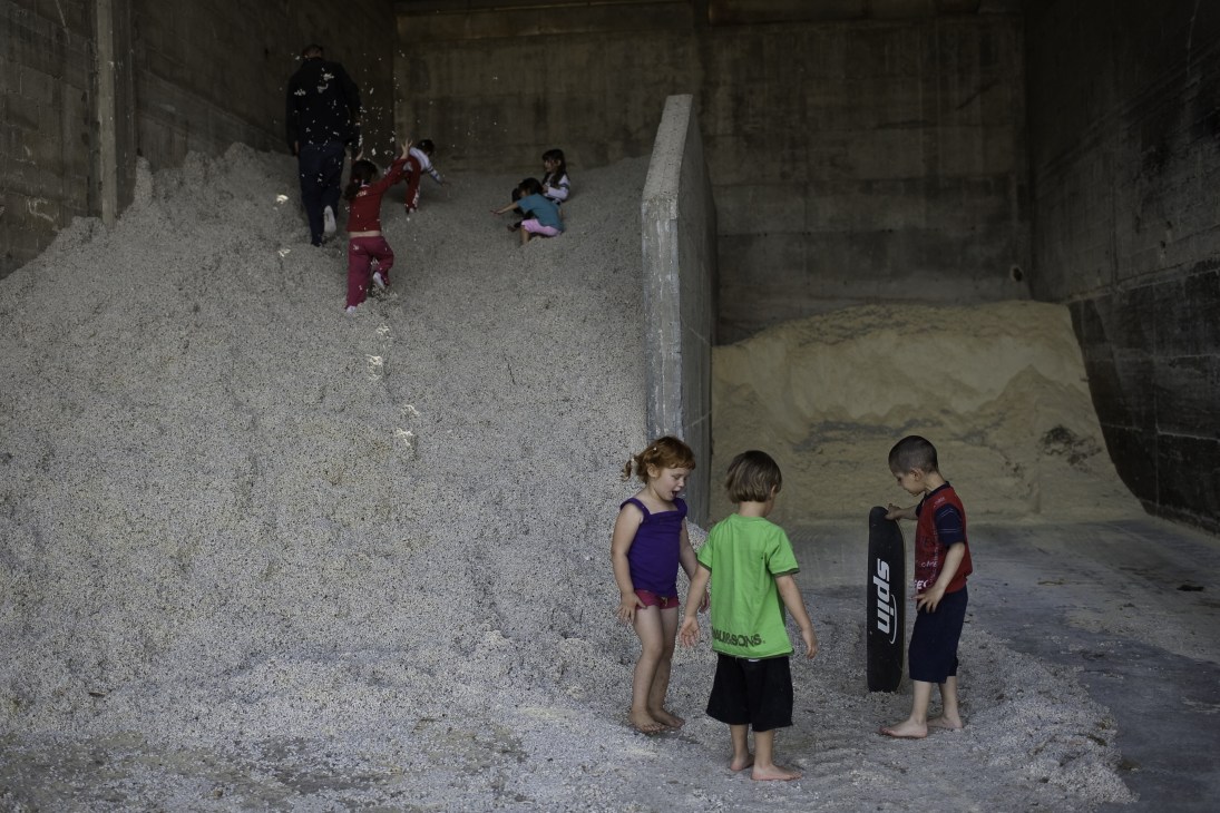 Children playing on a large pile of cotton in a concrete industrial space at Ma'agan Michael kibbutz.