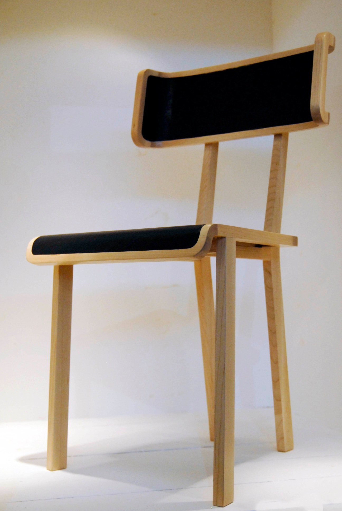 Albion chair by Sebastian Herkner with wooden frame and black upholstered seat and backrest.