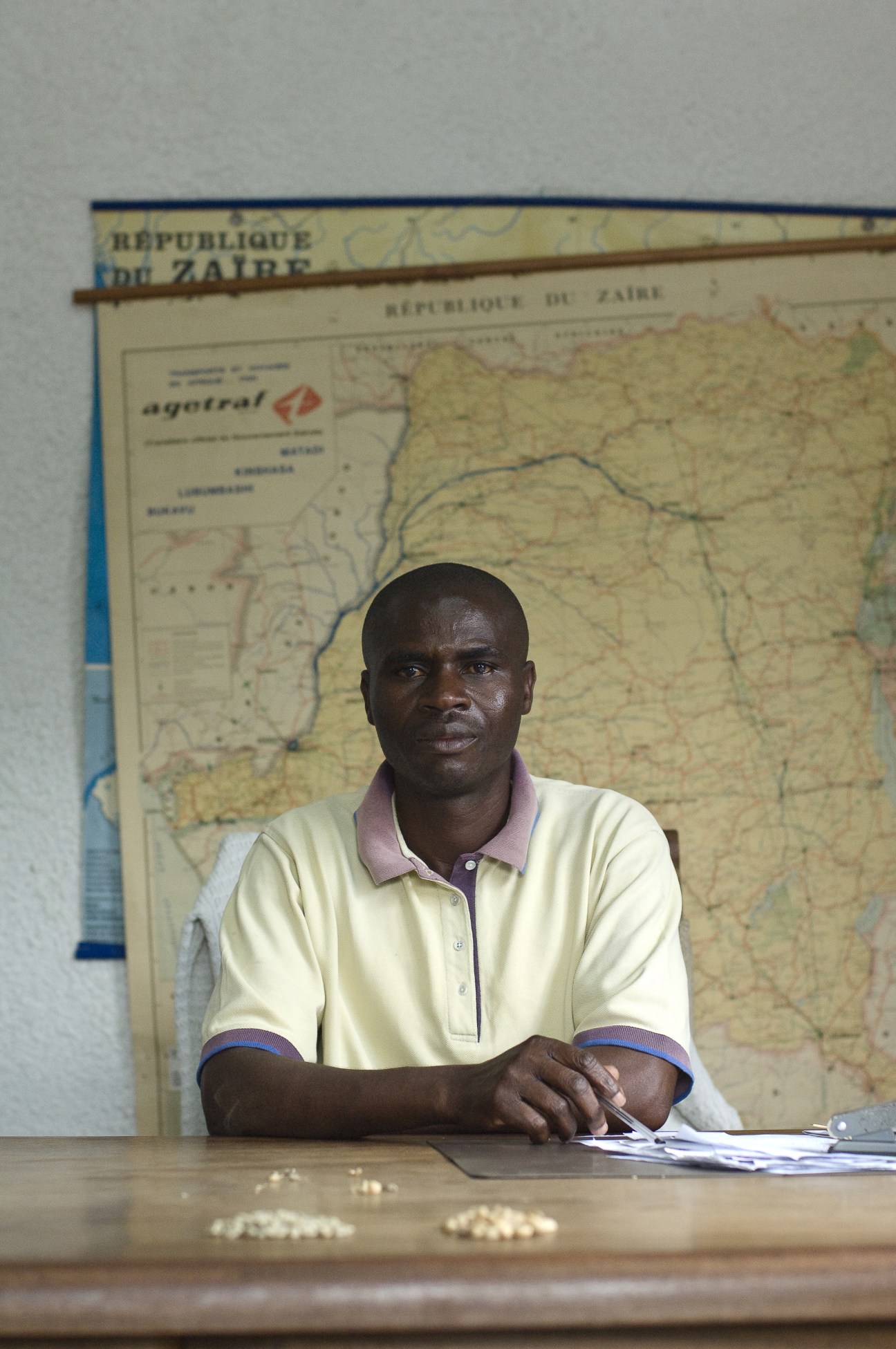 Michel Mwengeherwa sits at a desk with a map of the Democratic Republic of Zaire behind him.