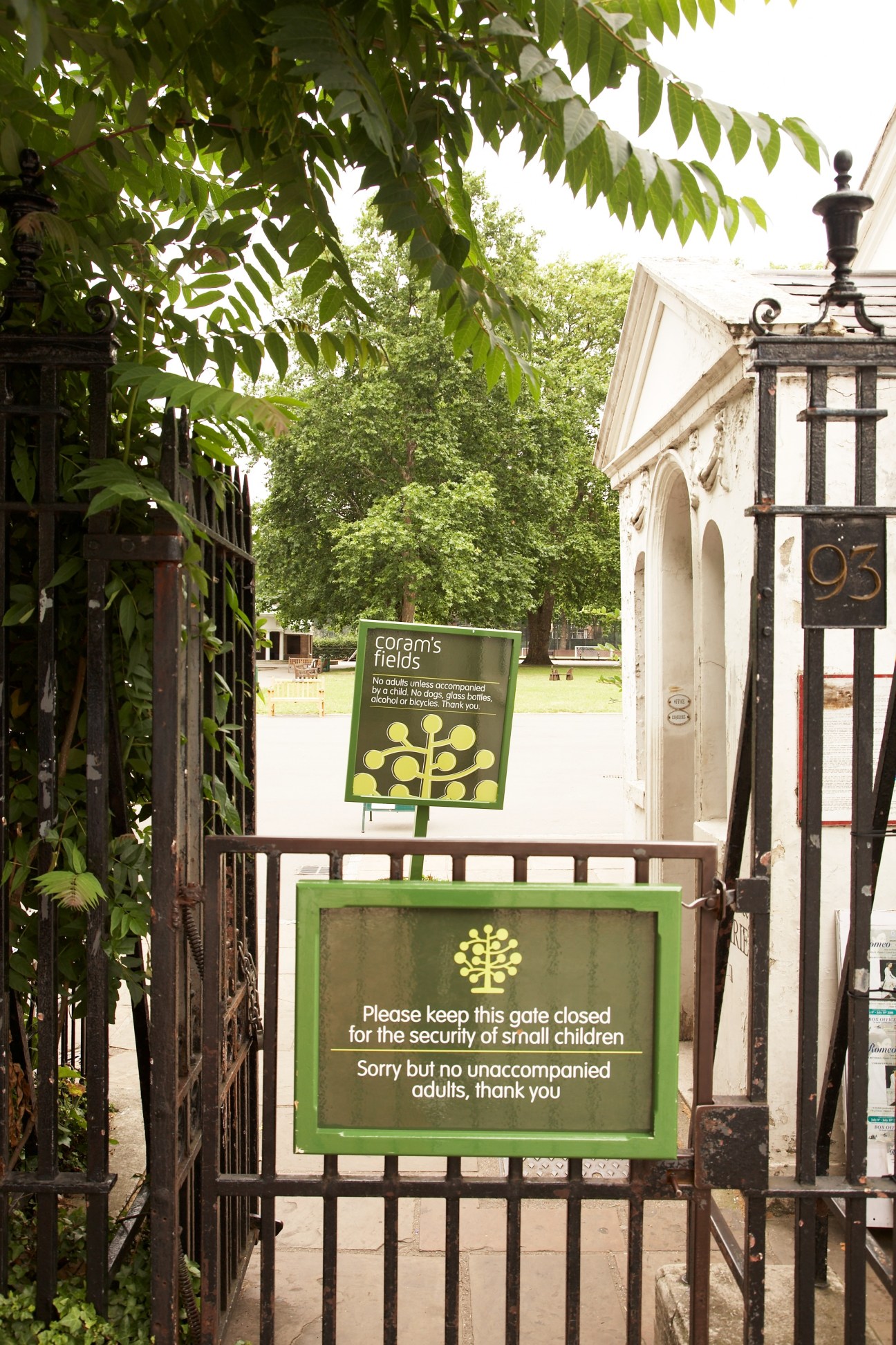 The green gate entrance to Coram's Fields with signs restricting access to unaccompanied adults.