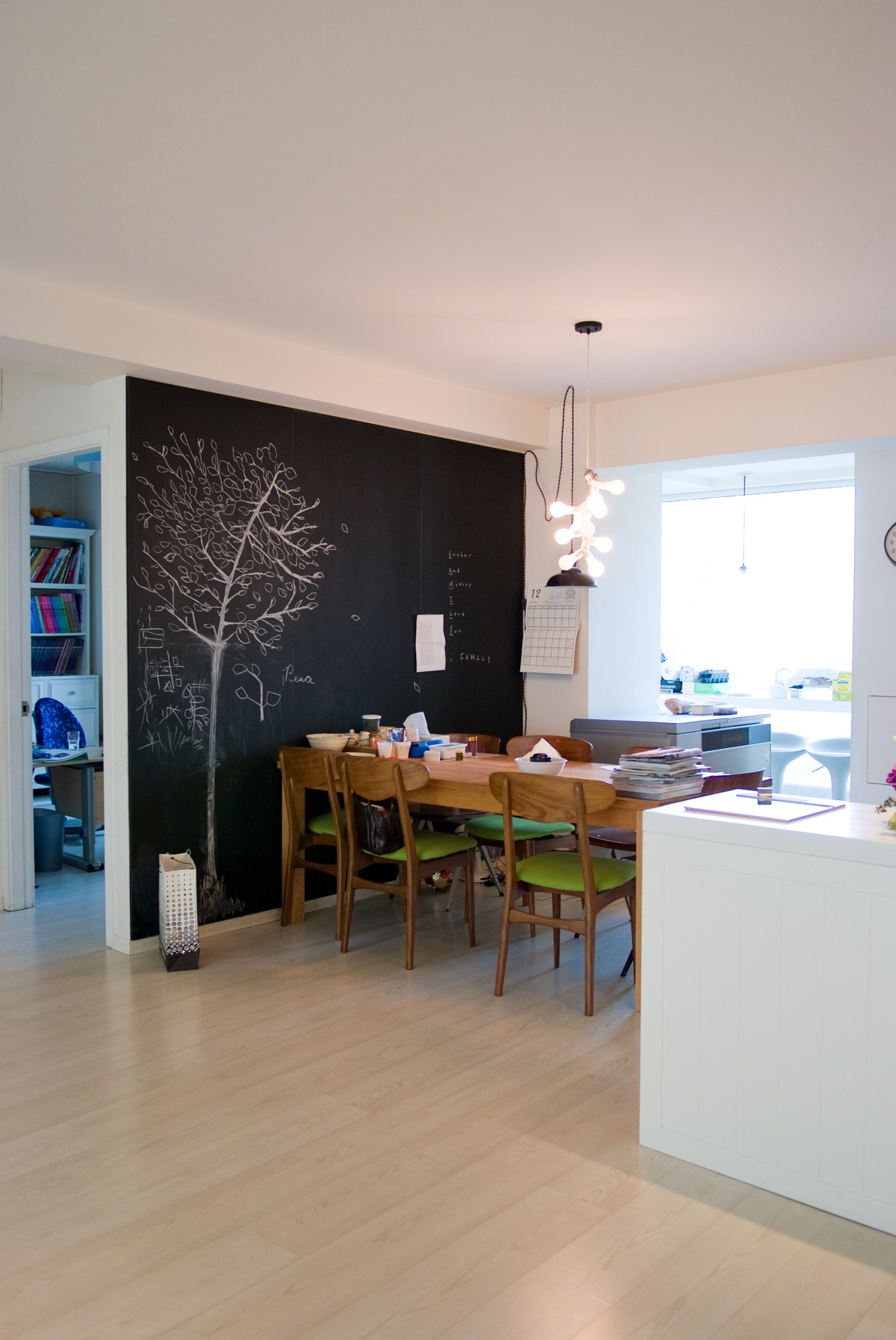 Modern apartment interior with wooden dining table, chalkboard wall, and contemporary furnishings overlooking Dosan Park in Seoul.