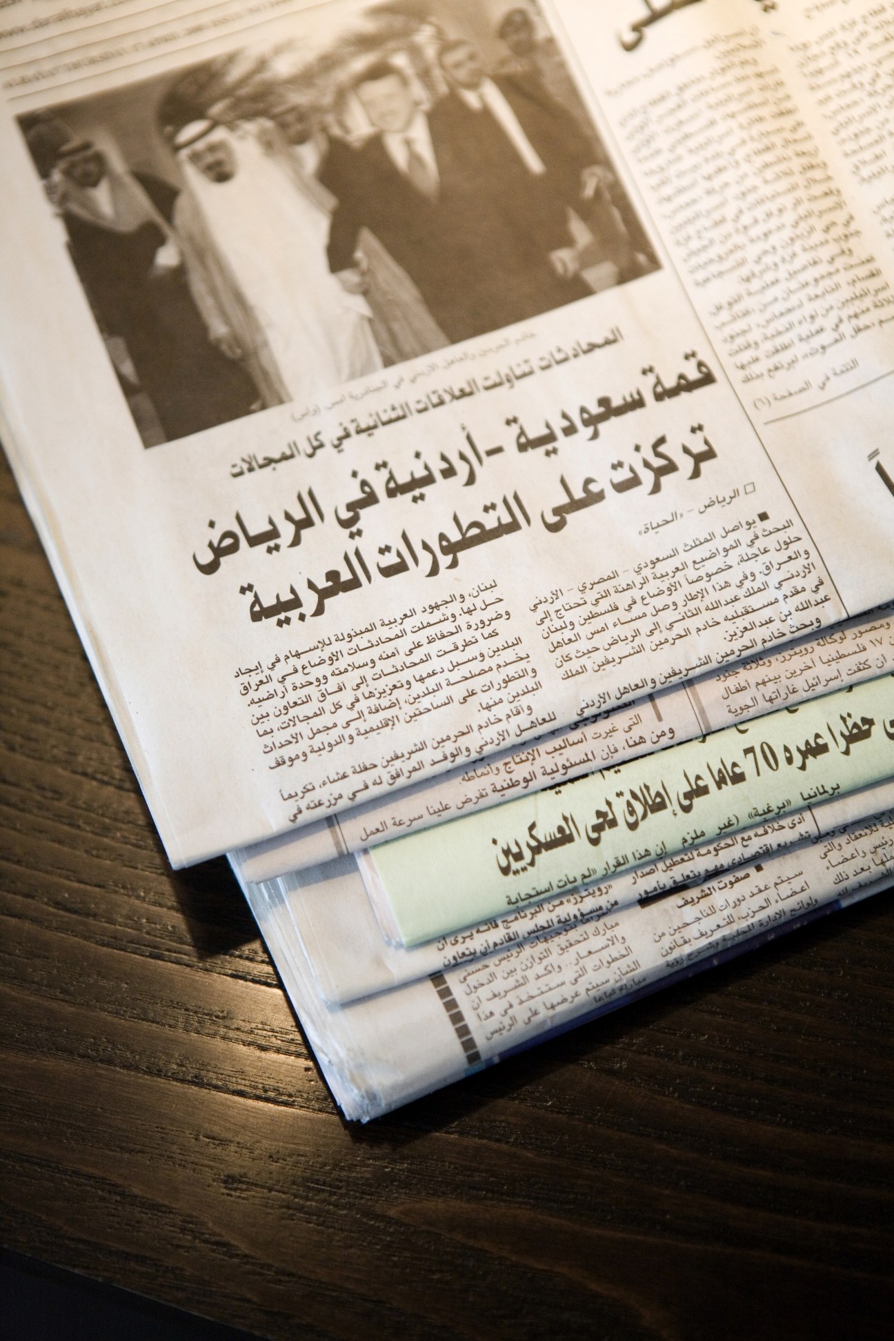 Stack of Arabic newspapers with a photograph of men in traditional dress on the front page