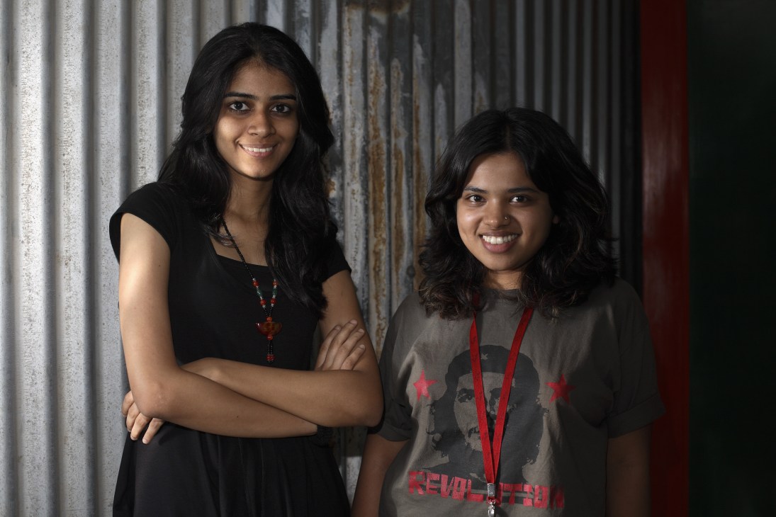 Two young women interns at Ogilvy advertising agency in Mumbai pose together against a corrugated metal backdrop.