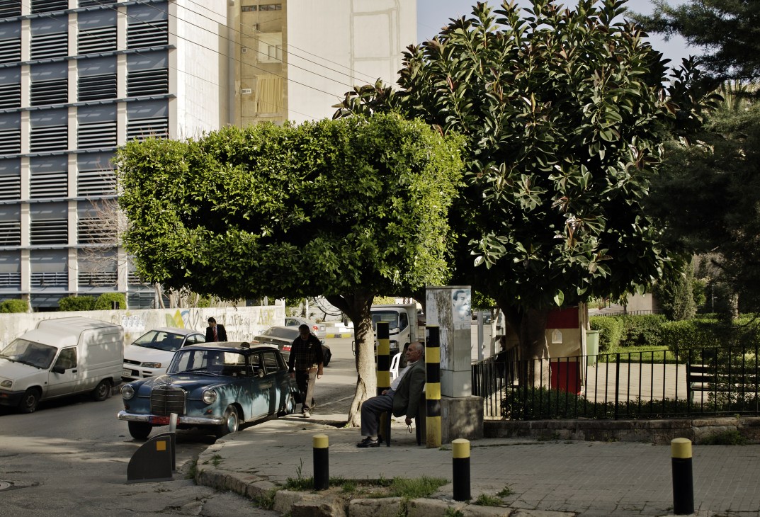 Street scene at Saint Nicolas Square in Ashrafieh with vintage car, modern building, and large trees.