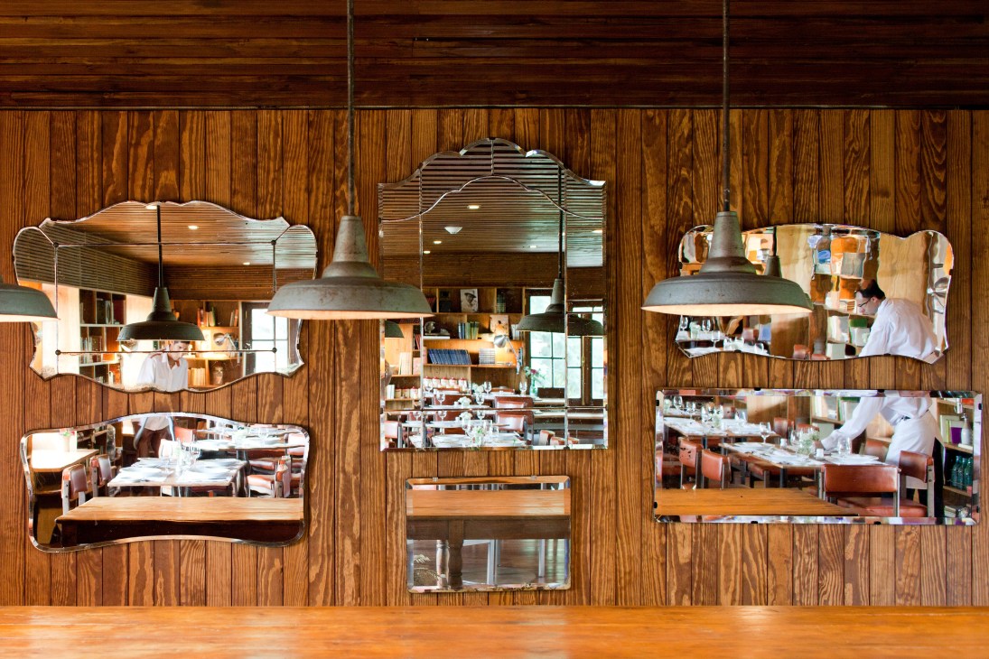 Las Piedras restaurant interior with wood-paneled walls, decorative mirrors, and industrial pendant lights.