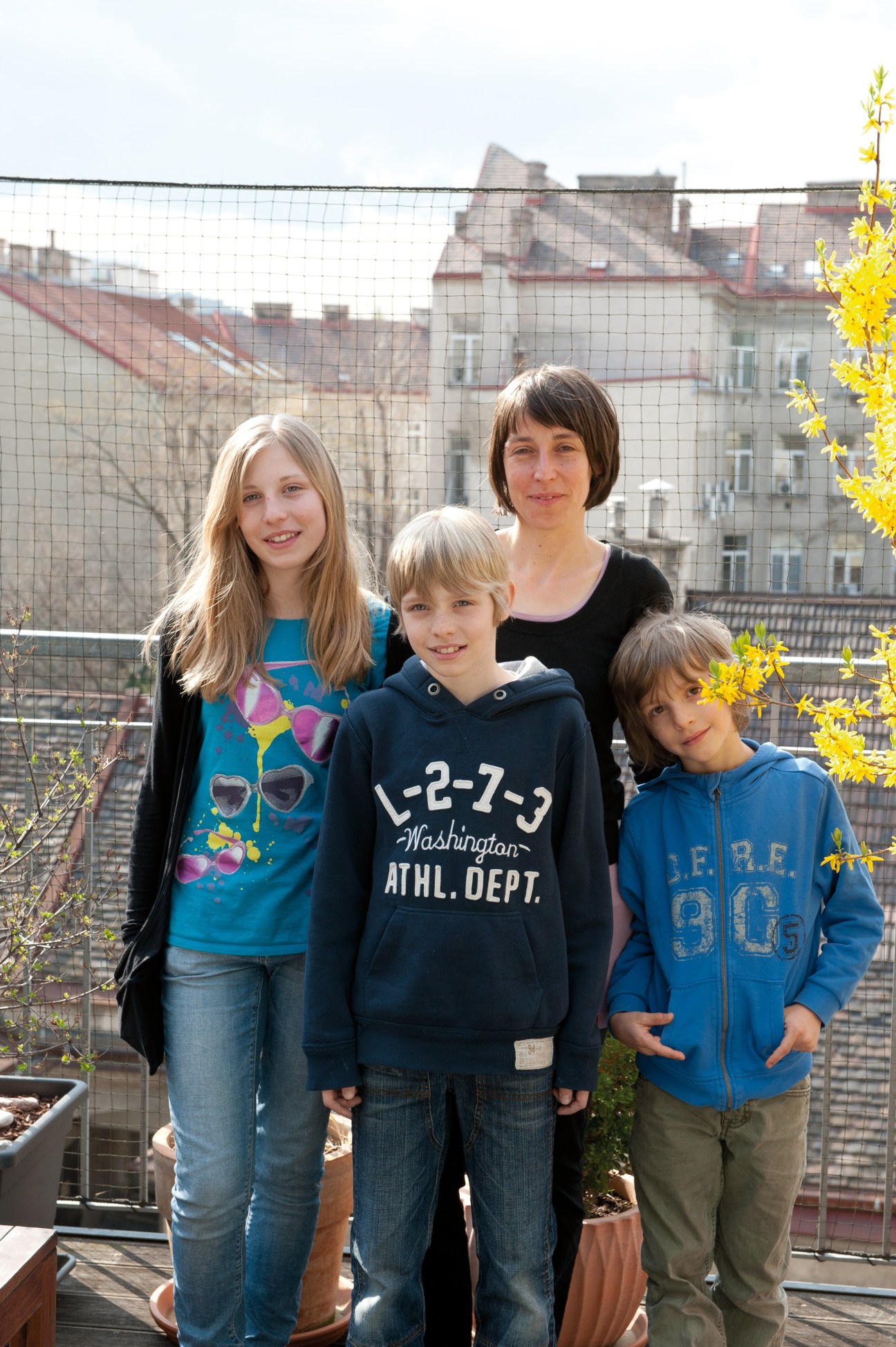 Lisa Höfling and her three children stand on a roof terrace overlooking Leopoldstadt buildings in Vienna.