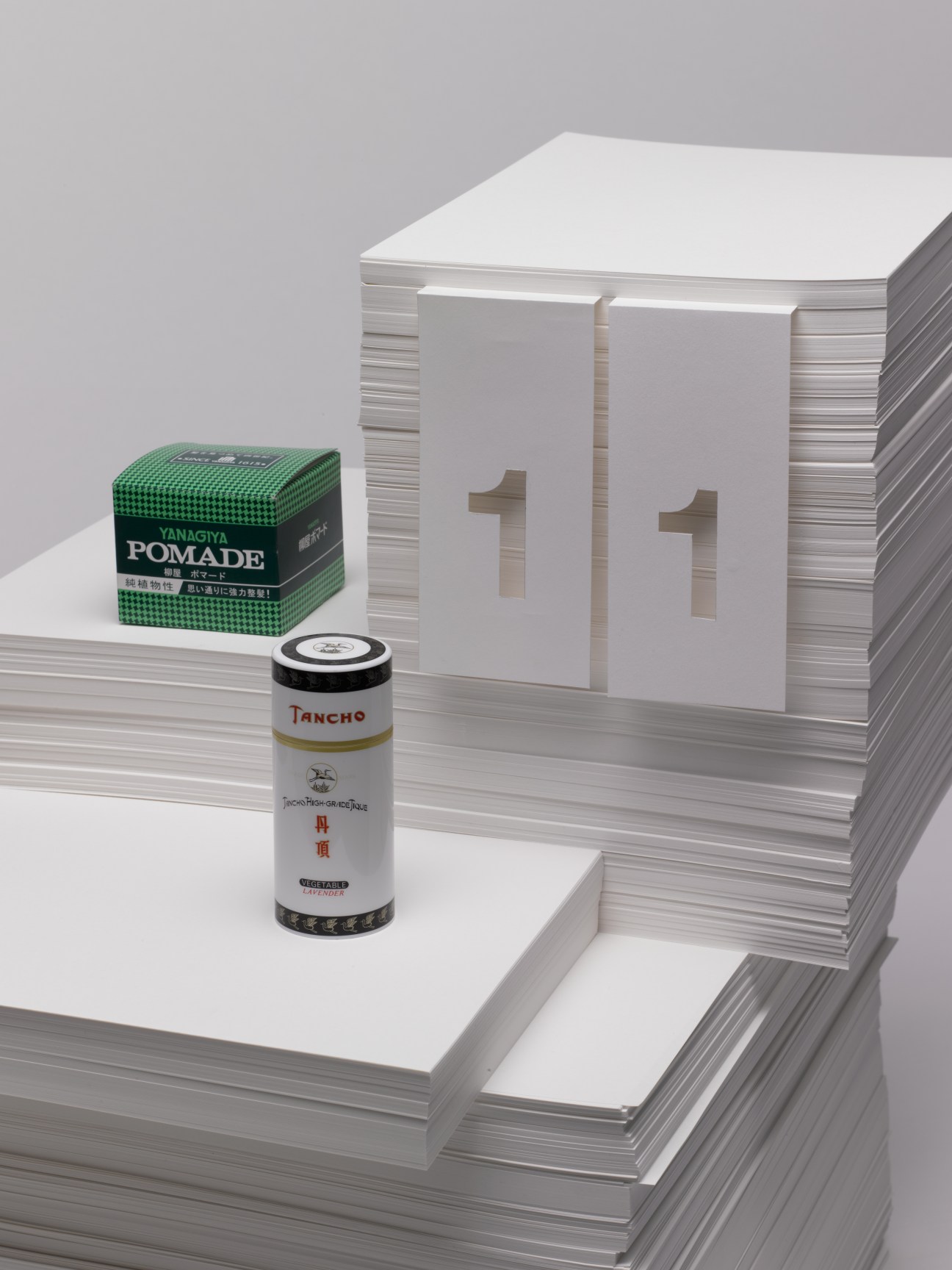 Tancho hair wax and Yanagiya pomade displayed with twelve monthly notebooks featuring numbered pages.