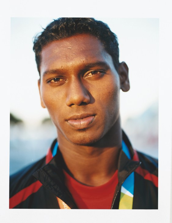 Male athlete from Indian track team wearing black and red competition jacket