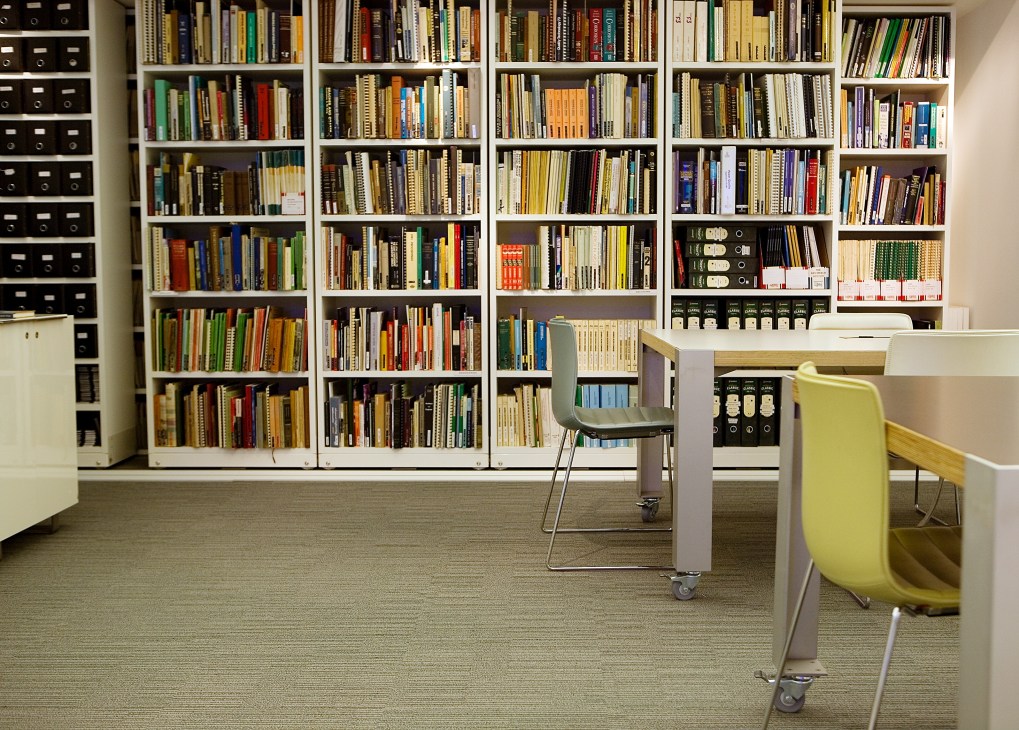Reference library at Arup's London headquarters with extensive bookshelves and a mobile desk with green chair.