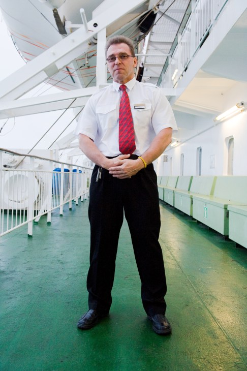 Barman Timo Krusell stands on the M/S Gabriella ship deck wearing a white shirt and red tie.