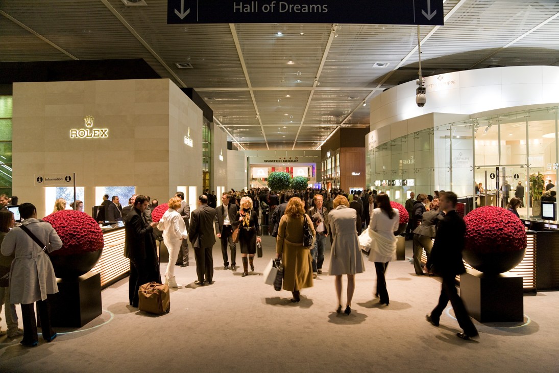 Crowded hallway in the Hall of Dreams at Baselworld with Rolex and Swatch Group booths flanking attendees.