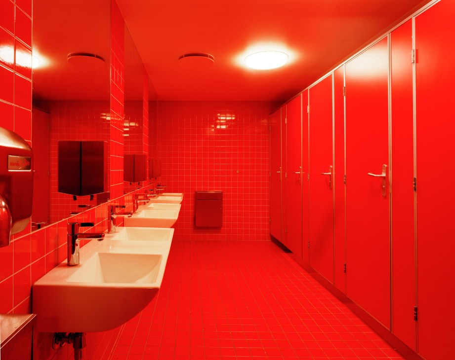 Girls' bathroom at Oslo International School with floor-to-ceiling red tiles, white sinks, and modern lighting fixtures.