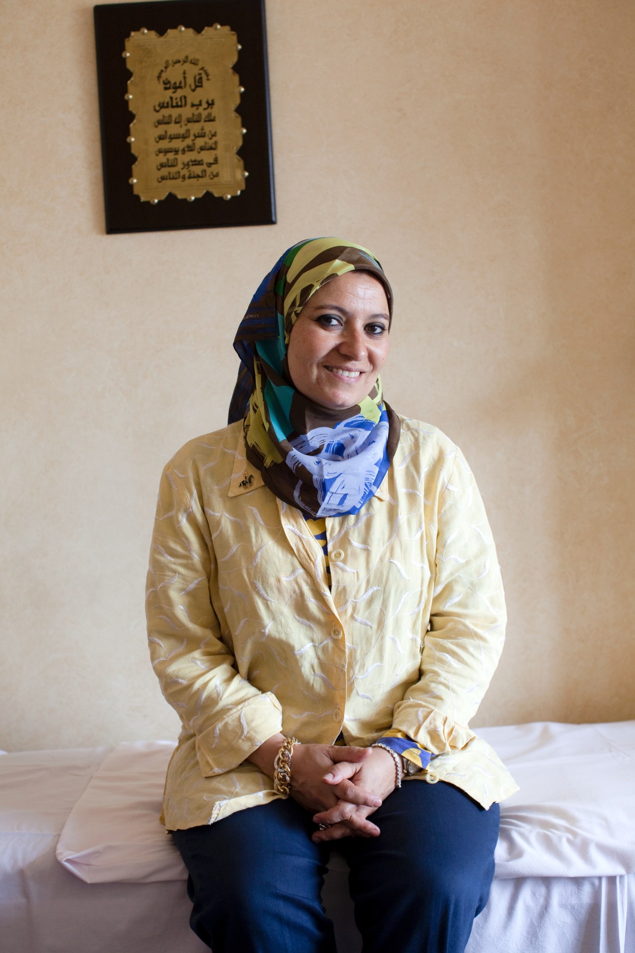 Heba Kotb, an Egyptian sexologist and surgeon, sitting in her office wearing a hijab and yellow jacket.