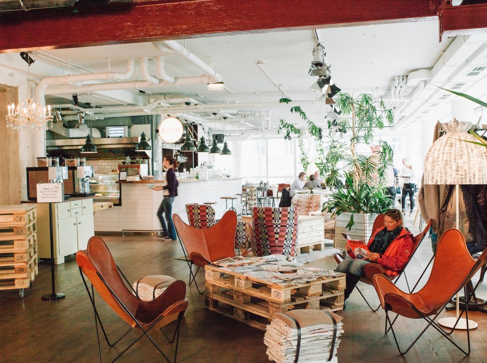 Hotel Daniel Vienna lobby with red leather butterfly chairs, wooden pallet table, and bright industrial interior with kitchen area.