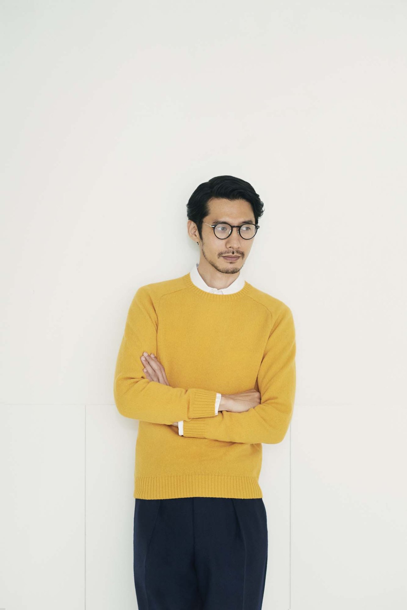 Man wearing yellow Beams Plus jumper with white Sunspel shirt collar visible, dark trousers, and Eyevan 7285 glasses.
