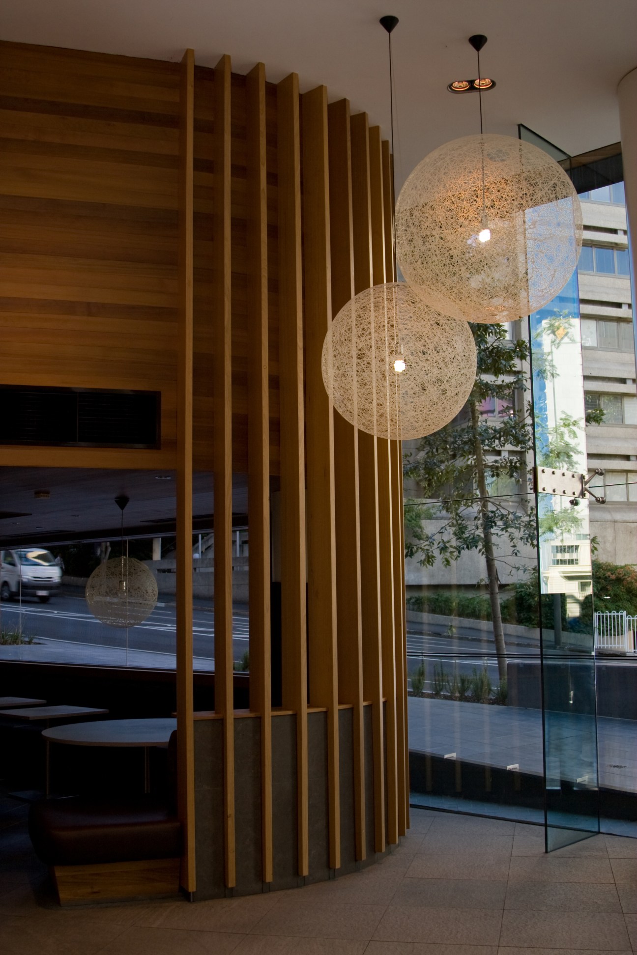 Modern foyer interior with wooden slat wall divider and spherical woven pendant lights.