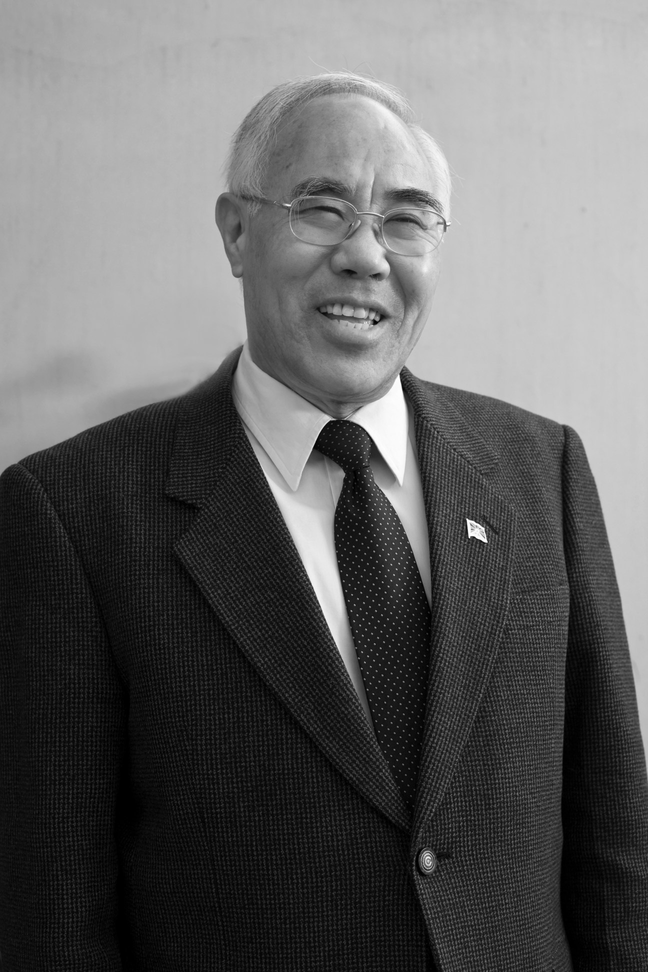 Tempa Tsering, main representative of the Dalai Lama, smiling in formal business attire with glasses.