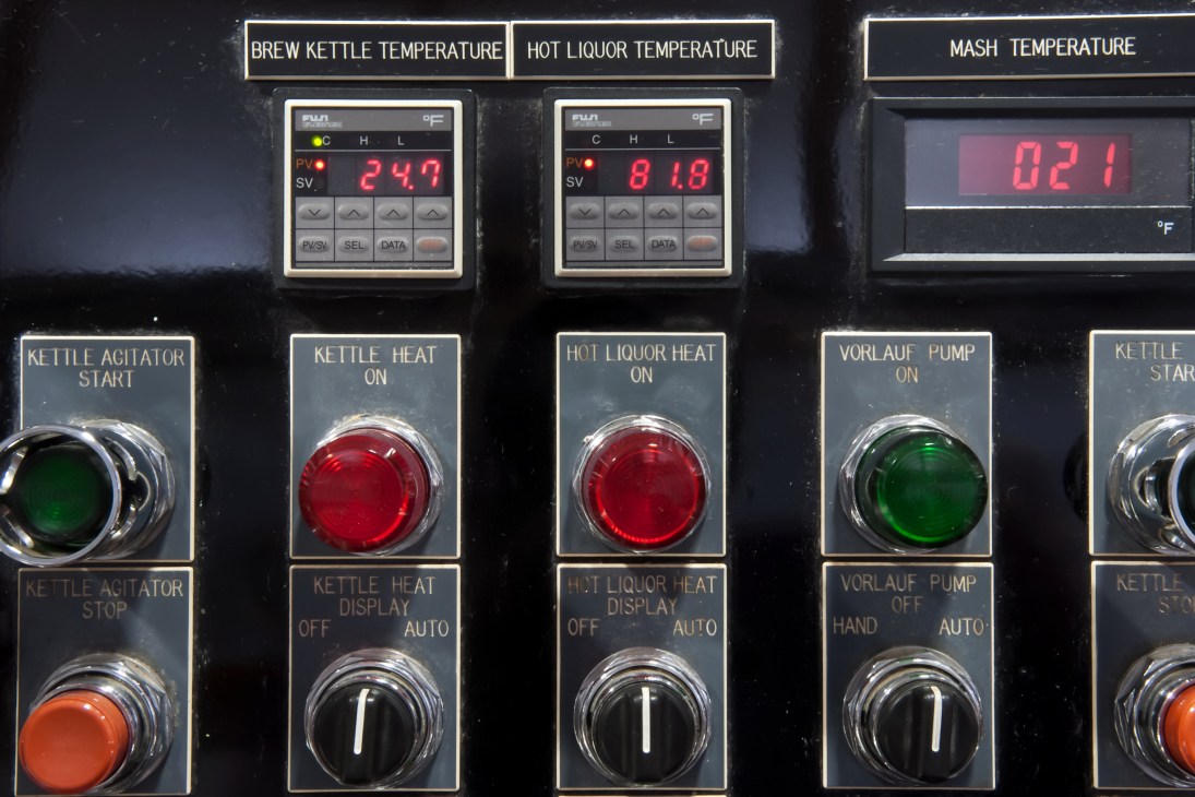 Brewery control panel with digital temperature displays and illuminated push buttons for kettle operations.