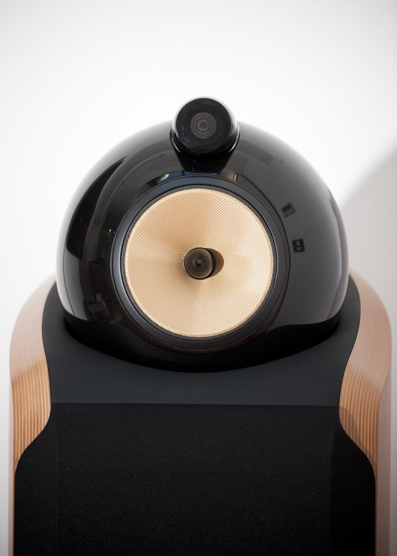 Black speaker with cream-colored woven cone and wooden side panels designed by Native for Bowers and Wilkins.
