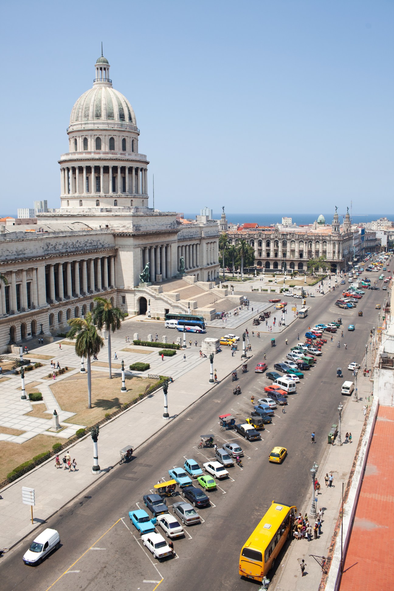 Aerial view of Havana's Capitolio building with its distinctive dome, surrounded by parked vintage cars and city streets below.