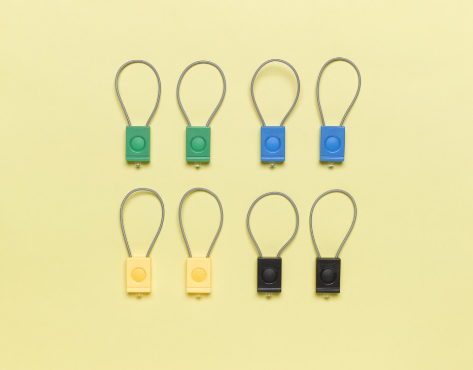 Eight colorful bicycle lights by Bookman in green, blue, yellow, and black arranged on a pale yellow background.