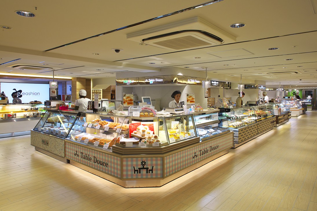 Interior of Eki Marché food hall in Osaka Station with multiple vendor stalls displaying prepared foods and baked goods.